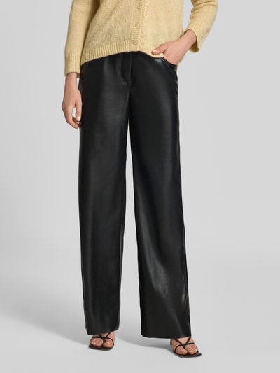 Frauenmodel trägt Straight Fit Hose mit Eingrifftaschen von Marc Cain in schwarzer Leder-Optik mit Gürtelschlaufen, Nahaufnahme Oberkörper.