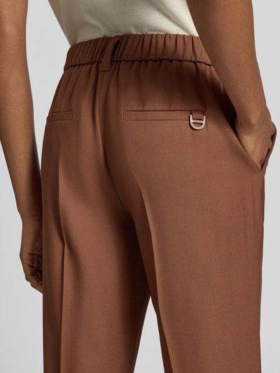Frauenmodel trägt Straight Fit Hose aus reiner Schurwolle Modell 'Luggioso' von Marella, glatte Textur in Braun, verkürzte Passform, Nahaufnahme Rückansicht.
