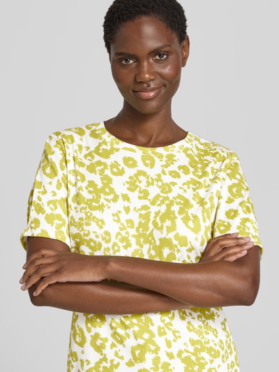 Frauenmodel trägt T-Shirt im Allover-Look mit Rundhalsausschnitt von Marc Cain, gelb-weißes Muster, Baumwoll-Elasthan-Mix, Regular Fit, Nahaufnahme Oberkörper.