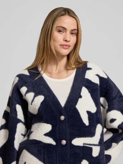 Frauenmodel trägt Comfort Fit Strickjacke mit Allover-Muster Modell 'JARDEN' von Essentiel Antwerp, Strick, Nahaufnahme Oberkörper.