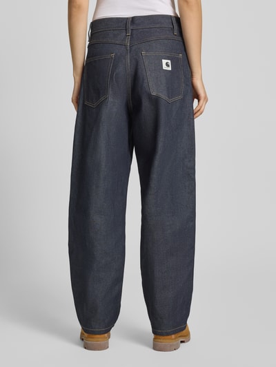 Frauenmodel trägt Jeans mit weitem Bein Modell 'Brandon' von Carhartt Work In Progress aus reiner Baumwolle, dunkles Blau, Ganzkörperansicht Rückansicht.