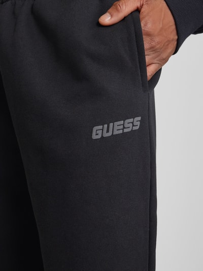 Guess Activewear Spodnie dresowe o kroju relaxed fit z nadrukiem z logo model ‘EMIS’ Czarny 3