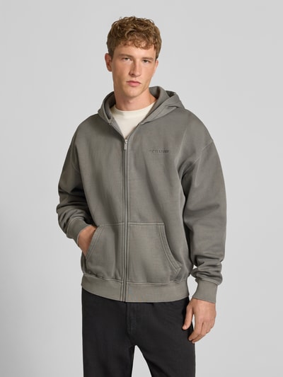 Männermodel trägt Regular Fit Sweatjacke aus Baumwoll-Mix von PEGADOR in Grau mit Logo-Stickerei, Kängurutasche, Zipper, Ganzkörperansicht von vorne.