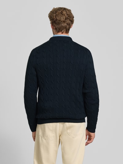 Männermodel trägt Regular Fit Strickjacke aus reiner Baumwolle von Polo Ralph Lauren in Dunkelblau mit Zopfmuster, Ganzkörperansicht Rückansicht. Kontext: Herren Poloshirt von Polo Ralph Lauren.
