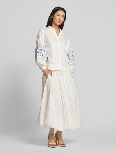 Modelka kobieca nosi Regular Fit Bluse mit Stitchings od HERZENS, biały bawełniano-elastanowy materiał, V-dekolt, guzik, widok całej sylwetki z przodu.