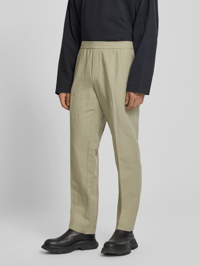 Mannelijk model draagt Straight Fit broek uit linnenmix van Filippa K in beige met persplooien en elastische band, gulp- en achterzakken, ganzekörpervooraanzicht.