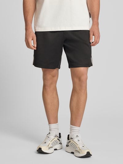Männermodel trägt Regular Fit Sweatshorts mit elastischem Bund Modell 'RIBER' von Only & Sons, Optik: Unifarben, Kontraststreifen, Eingrifftaschen, Ganzkörperansicht von vorne