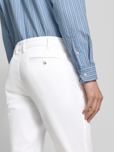 Mężczyznamodel nosi białe Straight Fit Chino mit Eingrifftaschen von MCNEAL z mieszanki bawełny, wpuszczane kieszenie, zapięcie na guzik i zamek błyskawiczny, szerokość w pasie 46 cm, długość wewnętrzna nogawki 81 cm, widok z tyłu, detal.