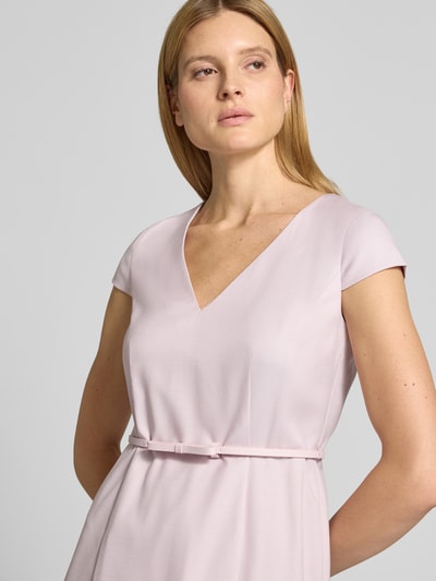 Frauenmodel trägt Knielanges Kleid mit Gürtel von Christian Berg Woman Selection, Material-Mix mit Viskose-Anteil, Fein strukturiert, V-Ausschnitt, A-Linie in zartem Rosaton, Nahaufnahme Oberkörper.