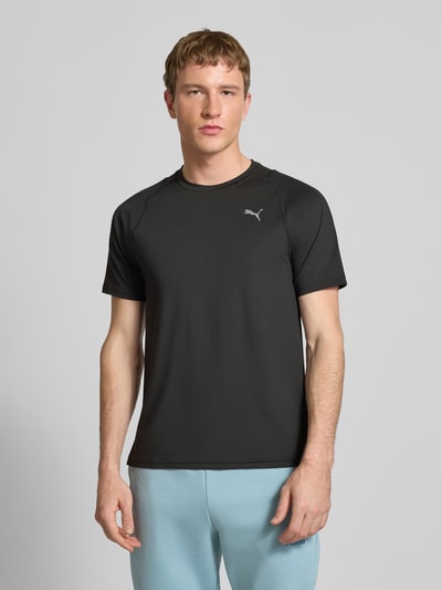 Männermodel trägt T-Shirt mit Label-Print von PUMA PERFORMANCE in Schwarz, Material-Mix mit Stretch-Anteil, Regular-Fit, Nahaufnahme Oberkörper.
