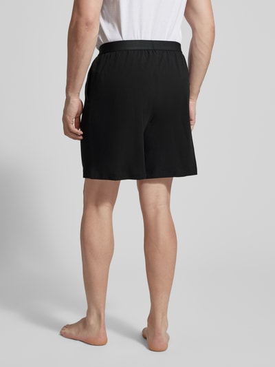 Männermodel trägt Regular Fit Sweatshorts aus Baumwoll-Mix von Tommy Hilfiger in Schwarz, unifarben, elastischer Bund, Ganzkörperansicht Rückansicht.