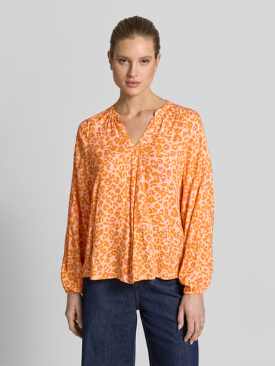 Frauenmodel trägt Damenbluse im Allover-Look mit V-Ausschnitt von Emily Van den Bergh, reine Viskose, orange gemustert, Ganzkörperansicht von vorne
