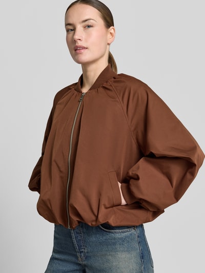 Frauenmodel trägt Blouson mit elastischen Ärmelabschlüssen und Reißverschluss von Zero in Braun, Loose-Fit, Raglanärmel, Nahaufnahme Oberkörper. Rückenlänge bei Größe 36: 52 cm, Schulterbreite: 40 cm, Brustweite: 50 cm, Ärmellänge: 55 cm.