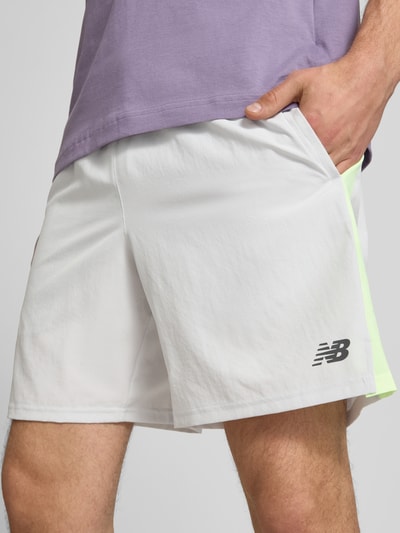 Männermodel trägt Shorts mit elastischem Bund und Logo von New Balance in Weiß mit Logo, Regular-Fit, Nahaufnahme Oberschenkel.