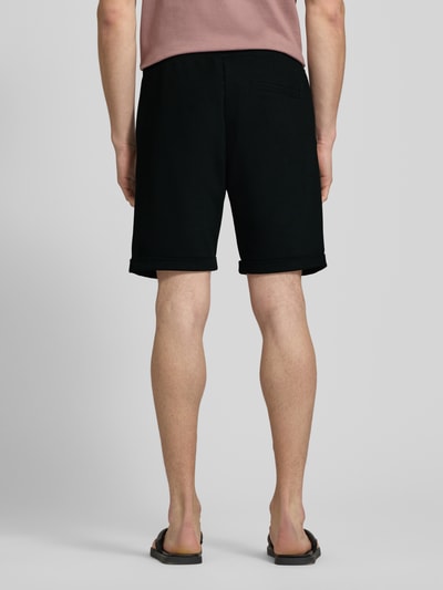 Männermodel trägt Shorts mit elastischem Bund und Gesäßtasche von MCNEAL in Schwarz, Regular-Fit, Material-Mix mit Viskose-Anteil, Ganzkörperansicht Rückansicht.
