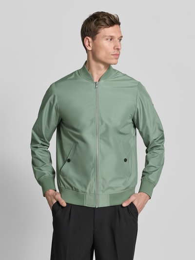 Männermodel trägt Jacke mit Stehkragen Modell 'clay' von Matinique in regular fit, grün mit ritssluiting und steekzakken, ganzkörperansicht von vorne