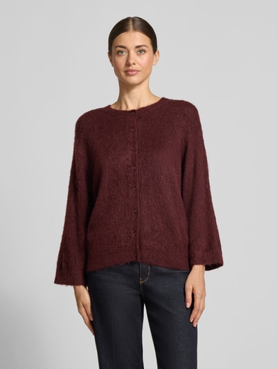 Kobiece model prezentuje Strickjacke aus Woll-Mohair-Mix Modell 'Disille' von OPUS, bordowy kolor, gładka faktura, okrągły dekolt, rękawy 3/4 z prążkowanym wykończeniem, dół prążkowany, widok całej sylwetki z przodu.