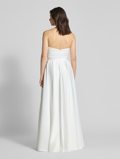 Frauenmodel trägt Brautkleid mit Herz-Ausschnitt von Mascara in Satin mit floraler Spitzenbesatz, Zierperlen und Maxilänge, Ganzkörperansicht Rückansicht.