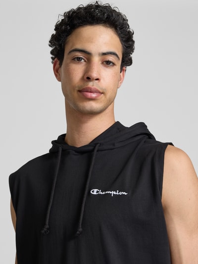 Männermodel trägt Hoodie mit Label-Stitching von CHAMPION in Schwarz, reine Baumwolle, Regular Fit, Nahaufnahme Oberkörper.