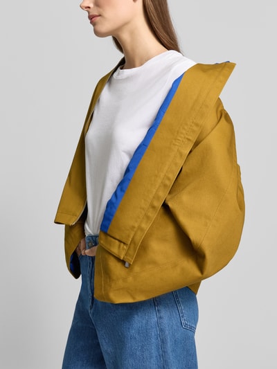 Modelka nosi Kurze Barn-Jacket mit Kontrast-Kragen - curated by Tinvcb od SIC, bawełna, krój relaxed fit, kołnierz wykładany, zamek, kolor musztardowy z niebieską podszewką, długość tyłu w rozmiarze 36: 56 cm, szerokość ramion w rozmiarze 36: 44 cm, szerokość klatki piersiowej w rozmiarze 36: 60 cm, długość rękawa w rozmiarze 36: 57 cm, jasne tło, widok na górną część ciała z boku