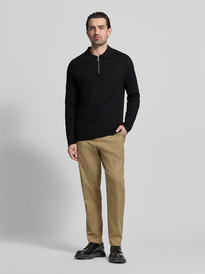 Männermodel trägt unifarbenen, schwarzen Relaxed Fit Pullover aus Viskose-Mix Modell 'TELLER' von SELECTED HOMME, Feinstrick, Polokragen, Ganzkörperansicht von vorne.