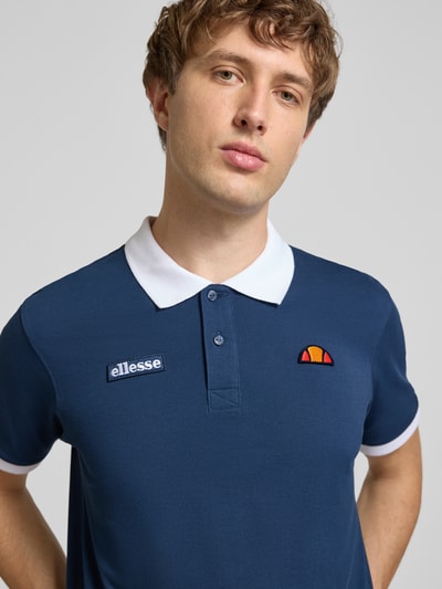 Männermodel trägt Regular Fit Poloshirt mit Label-Stitchings von ellesse, puur katoen, regular fit, knoopsluiting, ruglengte maat M 77 cm, nahaufnahme oberkörper.