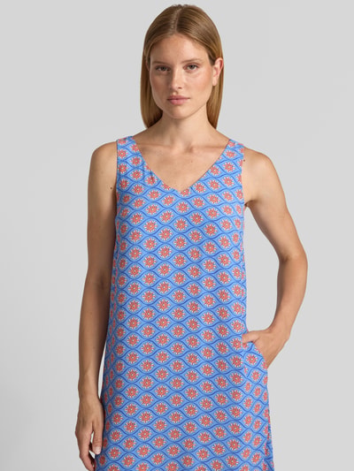Frauenmodel trägt Midikleid aus Viskose mit V-Ausschnitt von Smith and Soul im Allover-Look, Blau mit roten Mustern, Nahaufnahme Oberkörper.