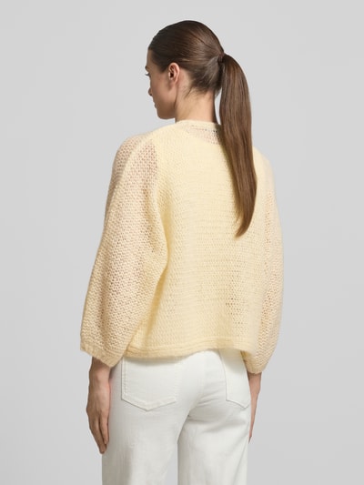 Frauenmodel trägt Relaxed Fit Cardigan mit Baby-Alpaka-Anteil Modell 'Tulea' von Someday in cremefarbenem Strick-Optik, Rückenlänge bei Größe 36: 51 cm, Ärmellänge bei Größe 36: 49 cm, Material-Mix, Ganzkörperansicht Rückansicht.