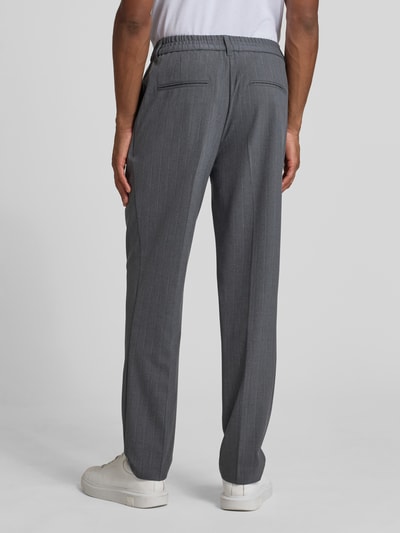 Männermodel trägt Straight Fit Stoffhose mit Bügelfalten Modell 'Marc' von Casual Friday, Elastischer-Material-Mix mit Viskose-Anteil, Ganzkörperansicht Rückansicht.