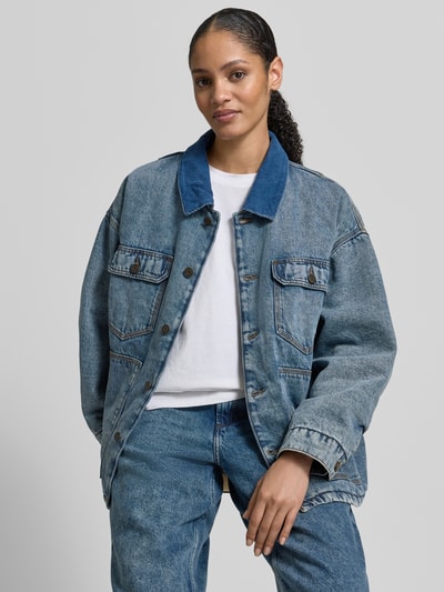 Frauenmodel trägt Jeansjacke mit Knopfleiste von American Vintage in Blau, Reine Baumwolle, Lockerer Schnitt, Kentkragen, Nahaufnahme Oberkörper.