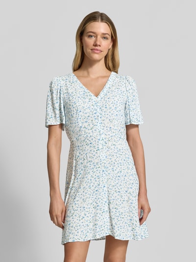 Frauenmodel trägt Leicht ausgestelltes Minikleid aus reiner Viskose Modell 'ALBA' von Vero Moda, Optik: Unifarben, Passform: Leicht ausgestellt, Länge: Mini, Ausschnitt: V-Ausschnitt, Taillengürtel, Knopfleiste, Ärmelform: Kurzarm, Material: Reine Viskose, Ganzkörperansicht von vorne.