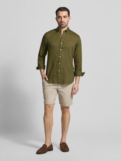 Männermodel trägt Regular Fit Freizeithemd aus reinem Leinen von Polo Ralph Lauren in Olivgrün, uni, Knopfleiste, Ganzkörperansicht von vorne.