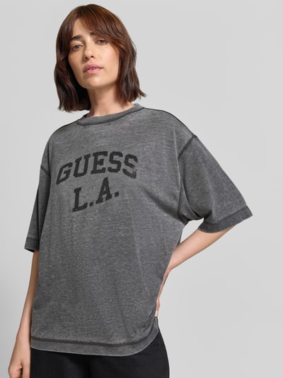 Frauenmodel trägt Oversized T-Shirt mit Ziersteinbesatz und Rundhalsausschnitt von GUESS, grau, Baumwoll-Mix, Label-Print, Ganzkörperansicht von vorne.