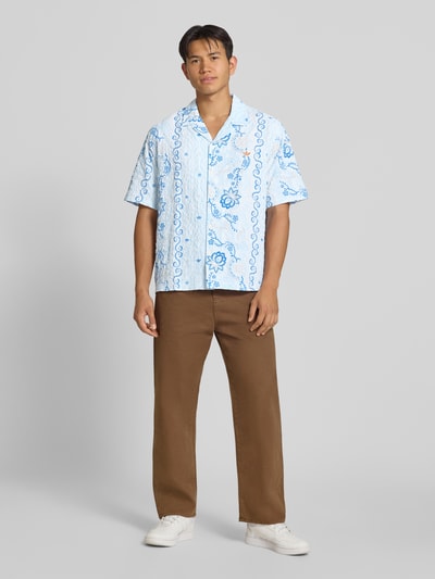 Männermodel trägt Relaxed Fit Freizeithemd aus Seersucker mit Logo-Stitching von adidas Originals, hellblau mit Muster, Ganzkörperansicht von vorne.