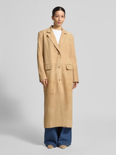 Frauenmodel trägt Ledermantel mit Pattentaschen Modell 'Santara' von STAND STUDIO aus beigem Ziegenvelours, gerader Schnitt, Ganzkörperansicht von vorne.