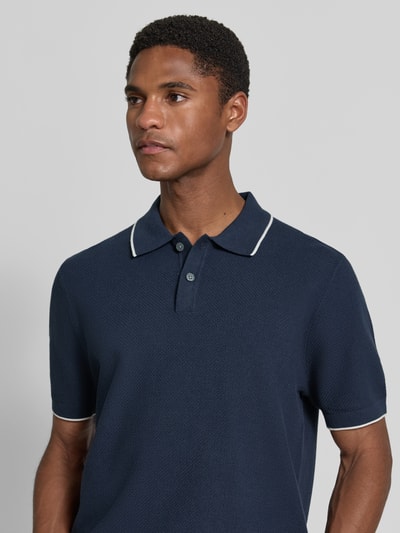 Männermodel trägt Regular Fit Poloshirt mit Kontrastkante von Christian Berg Men aus Reine Baumwolle mit Strukturmuster, Polokragen, Knopfleiste, Dunkelblau mit weißen Kontrasten, Ganzkörperansicht von vorne.