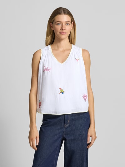 Frauenmodel trägt Blusentop mit Stitchings von Marc Cain aus reiner Baumwolle, weiß mit bunten Stickereien, Regular Fit, V-Ausschnitt, Ganzkörperansicht von vorne.