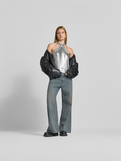 Frauenmodel trägt Top in Netz-Optik von Rabanne in Silber mit Stehkragen und Neckholder, kombiniert zu Jeans, Ganzkörperansicht von vorne.