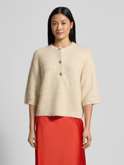 Frauenmodel trägt cremefarbenen Strickpullover mit 1/2-Arm Modell 'Ester' von GUIDO MARIA KRETSCHMER WOMAN, Knopfleiste, Regular Fit, Ganzkörperansicht von vorne.