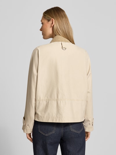 Modelka kobieca ma na sobie Jacke mit Zweiwege-Reißverschluss od Blonde No. 8, beżowa bawełna, luźny krój, długość tyłu w rozmiarze 36: 57 cm, szerokość ramion w rozmiarze 36: 42 cm, szerokość klatki piersiowej w rozmiarze 36: 80 cm, długość rękawa w rozmiarze 36: 60 cm, widok całej sylwetki od tyłu.