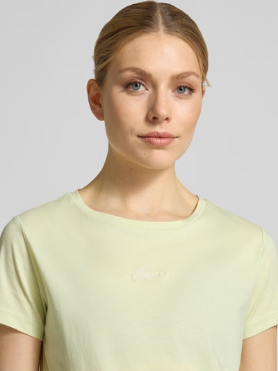 Frauenmodel trägt Slim Fit T-Shirt aus reiner Baumwolle Modell 'ELOVE_EMBRO' von BOSS Orange in unifarbenem Hellgelb mit Label-Stitching, Nahaufnahme Oberkörper.