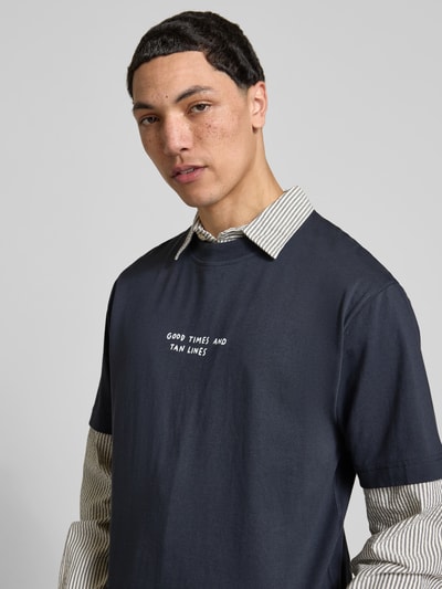 Männermodel trägt Regular Fit T-Shirt mit Statement-Print von Closed in Dunkelblau aus Reine Baumwolle, Nahaufnahme Oberkörper.