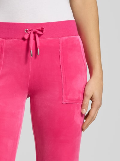 Kobiece model prezentuje Low Rise Sweatpants mit elastischem Bund Modell 'LAYLA' od Juicy Couture, mieszanka bawełny z dodatkiem streczu, rozkloszowany krój, niski stan, elastyczny pas, wpuszczane kieszenie, długość wewnętrzna nogawki w rozm. S: 39 cm, zbliżenie na górną część spodni.