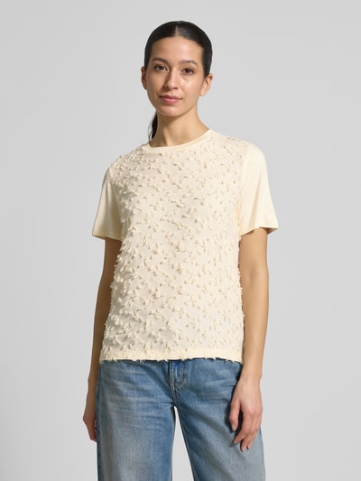Kobiece modelka nosi Regular Fit T-Shirt mit Viskose-Anteil od comma, damski t-shirt, mieszanka materiałów z dodatkiem wiskozy, ozdobne obszycie, okrągły dekolt, długość tyłu w rozmiarze 36: 55 cm, jasny kolor, przód teksturowany, pełny widok z przodu.
