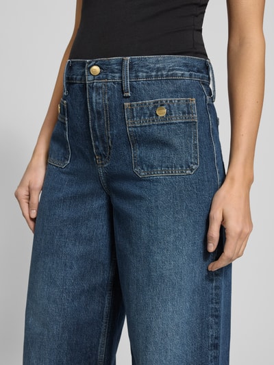 Frauenmodel trägt High Rise Jeans aus reiner Baumwolle Modell 'DNM MINE 70 S WIDE LEG HW' von Tommy Hilfiger in Denim-Optik, Wide Leg Passform, High-Waist, Label-Patch, Logo-Stitching, Gürtelschlaufen, Kontrastnähte, Knopf mit verdecktem Reißverschluss, Eingrifftaschen, Gesäßtaschen, Material Baumwolle; Nahaufnahme Hüft- und Beinbereich.