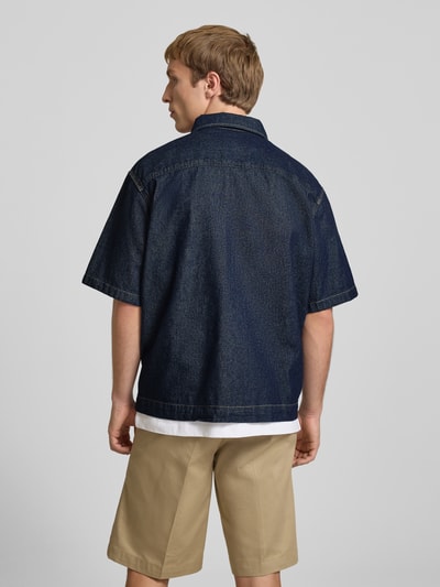 Männermodel trägt Relaxed Fit Jeanshemd mit Brusttasche van Dickies in donkerblauw, katoen, kentkraag, label-patch, rugaanzicht, context: heren jeanshemd, borstzak, knoopsluiting, ruglengte maat M 69 cm, schouderbreedte 44 cm, mouwlengte 27 cm. Ganzkörperansicht Rückansicht