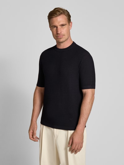 Männermodel trägt Slim Fit Strickshirt aus reiner Wolle von Emporio Armani in Dunkelblau, gerippte Abschlüsse, Kurzarm, Ganzkörperansicht von vorne.