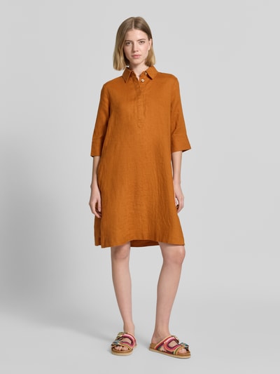 Frauenmodel trägt knielanges Hemdblusenkleid aus Leinen mit 3/4-Arm von Christian Berg Woman in A-Linie, rostbraune Farbe, Ganzkörperansicht von vorne. Man erkennt verdeckte Knopfleiste, Hemdblusenkragen und strukturierte, glatte Leinen-Textur. Rückenlänge bei Größe 36: 96 cm, Brustweite: 54 cm, Ärmellänge: 41 cm.