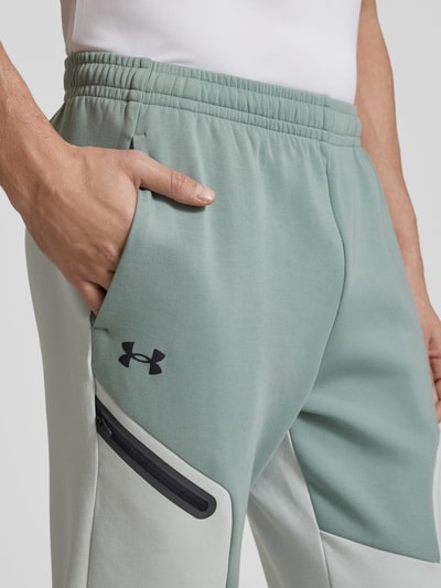 Under Armour Spodnie dresowe o kroju relaxed fit z nadrukiem z logo model ‘Unstoppable’ Miętowy 3