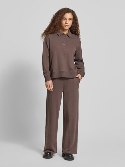 Vrouwenmodel draagt 'Sweatshirt mit Polokragen und Knopfleiste' van Gina Tricot, regular fit, polokraag, knoopsluiting, verlaagde schouders, donkerbruine kleur, gladde textuur, volledig lichaam aan de voorkant